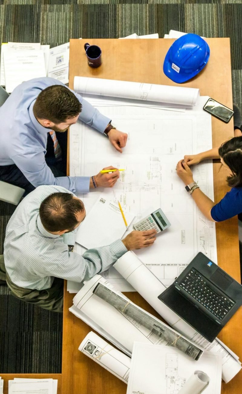 Top view of a team working on construction plans in an office setting.